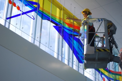 Charlotte Paul working on stained glass installation from boom lift